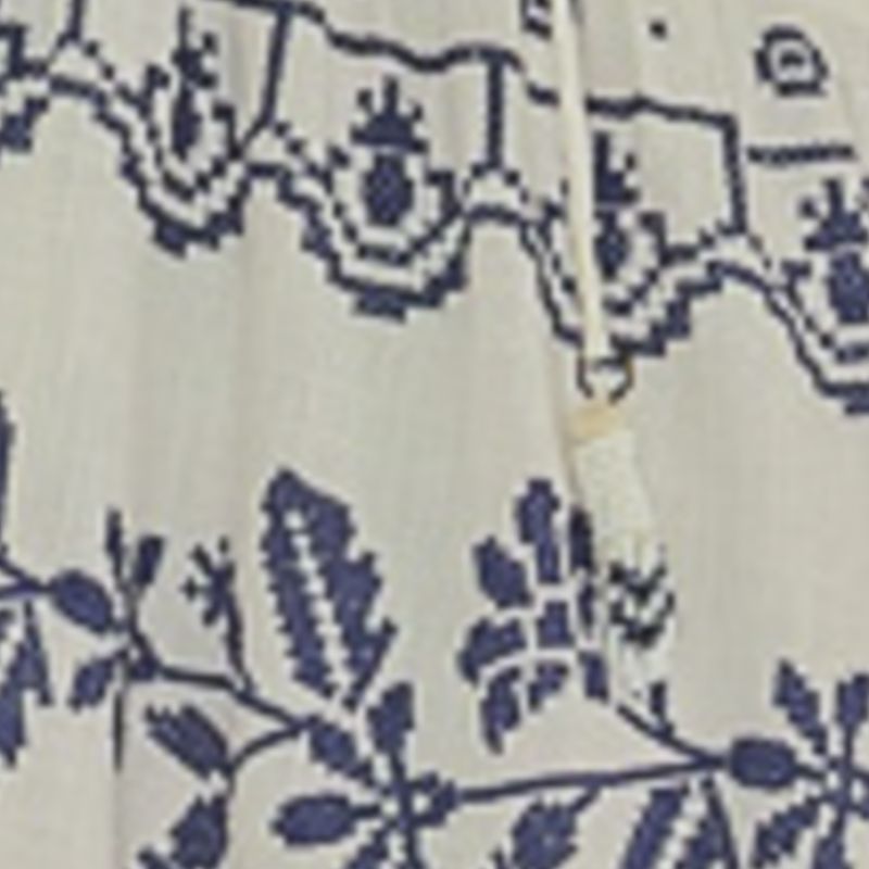 Vestido largo con bordado tropical azul sobre fondo claro, detalle del bordado en la parte superior trasera.