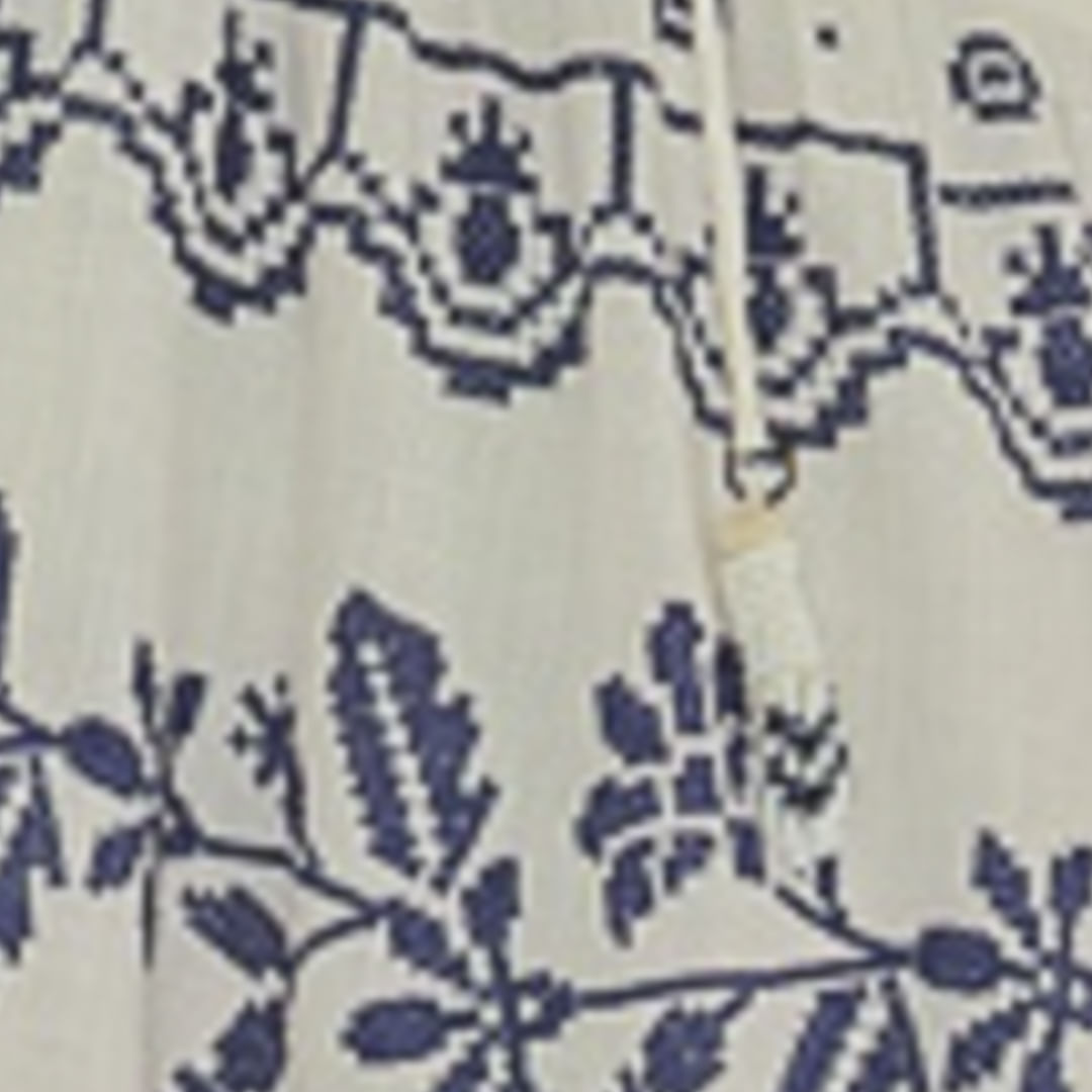 Vestido largo con bordado tropical azul sobre fondo claro, detalle del bordado en la parte superior trasera.