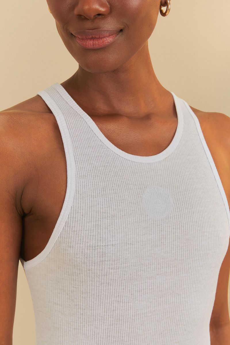 Detalle del escote redondo de la camiseta sin mangas blanca.