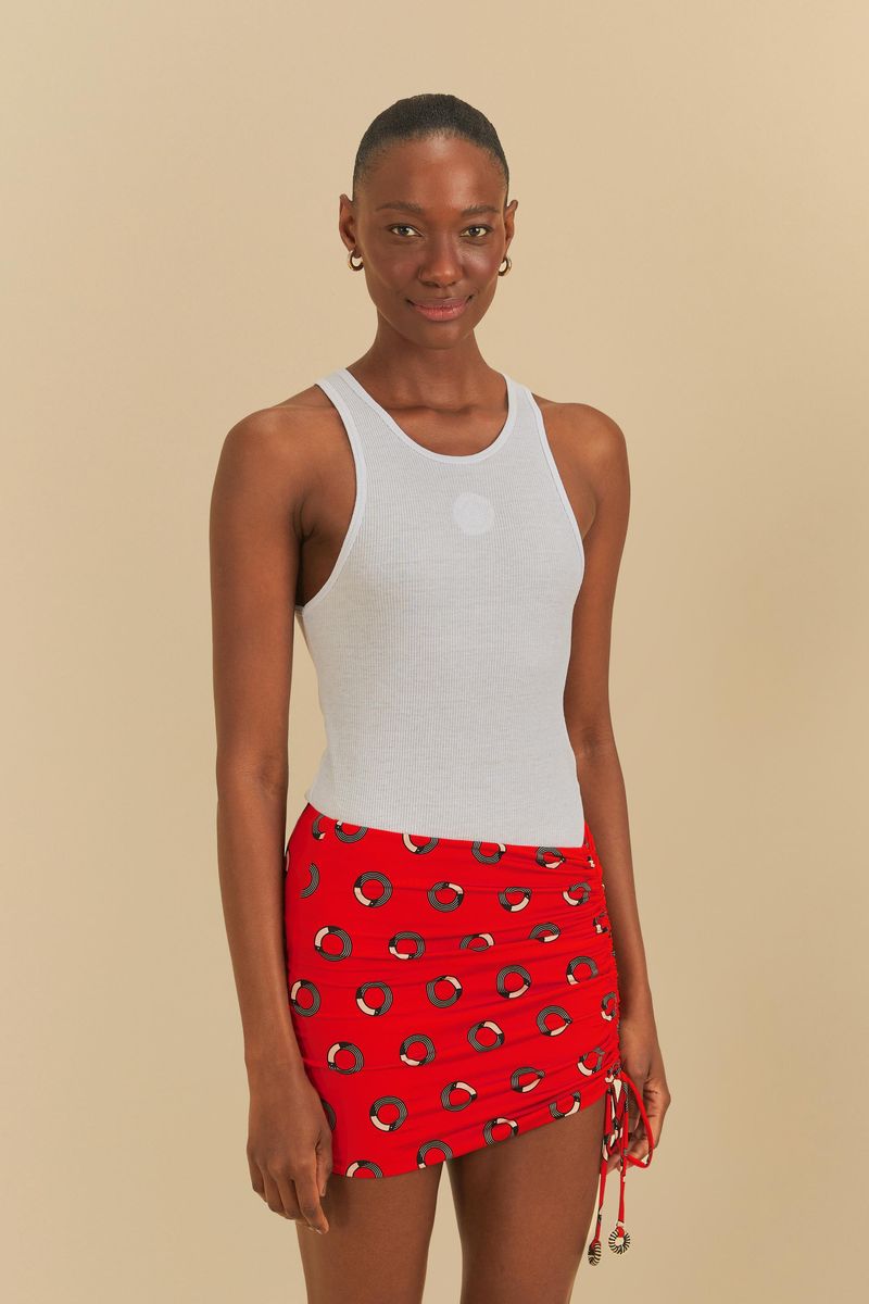 Camiseta sin mangas blanca vista desde el frente, combinada con una falda roja estampada.