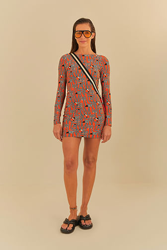 Vestido corto manga larga con estampado geométrico en fondo naranja, modelo en posición frontal.