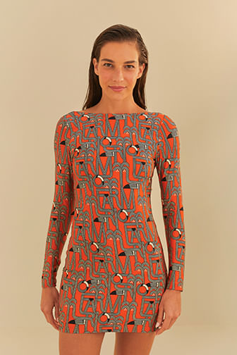 Vestido corto manga larga con estampado geométrico en fondo naranja, modelo en posición lateral.