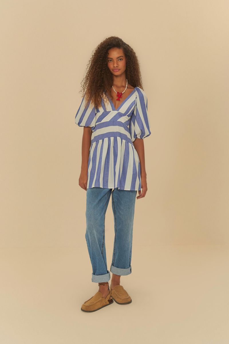 Vestido corto con mangas abullonadas y estampado de rayas azules y blancas, combinado con pantalones de mezclilla y zapatos marrones.
