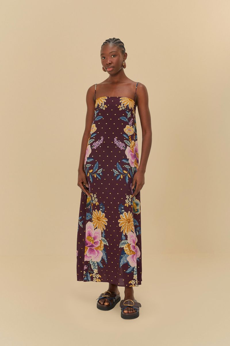 Vestido largo con estampado floral sobre fondo púrpura, tirantes delgados y caída fluida.
