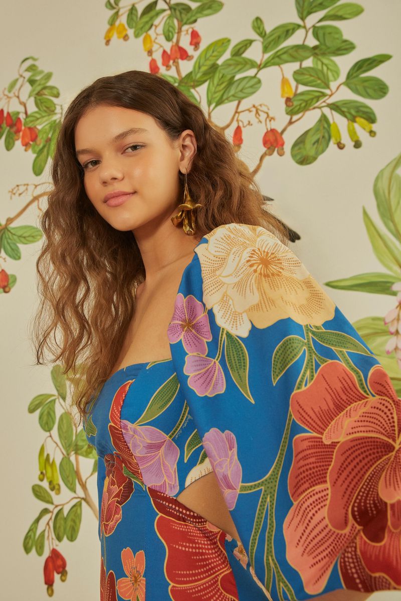 Detalle del vestido azul con estampado floral, mostrando el escote cuadrado y mangas amplias.