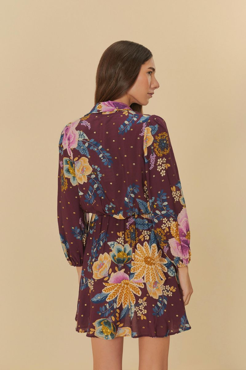 Vista trasera del vestido corto estampado con flores sobre un fondo morado, mostrando la caída y detalles de la espalda.