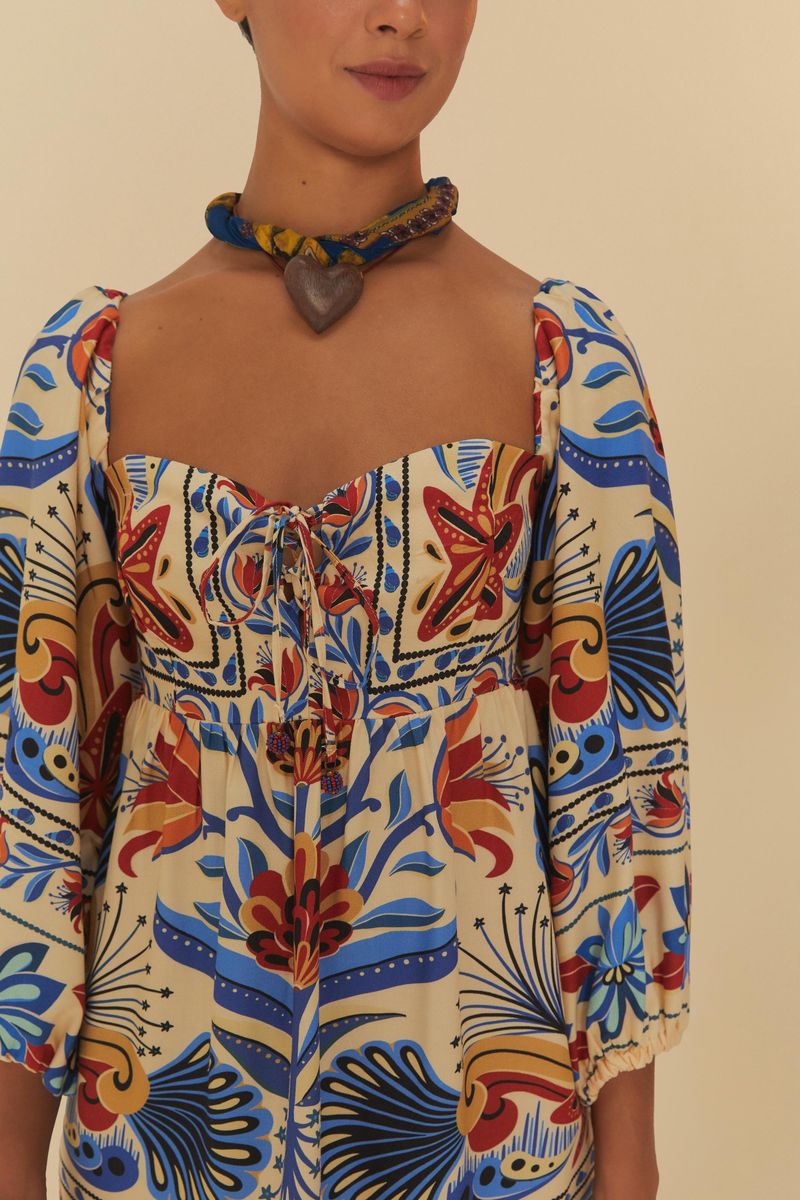 Primer plano del escote del vestido, destacando el diseño con lazada y estampado colorido.
