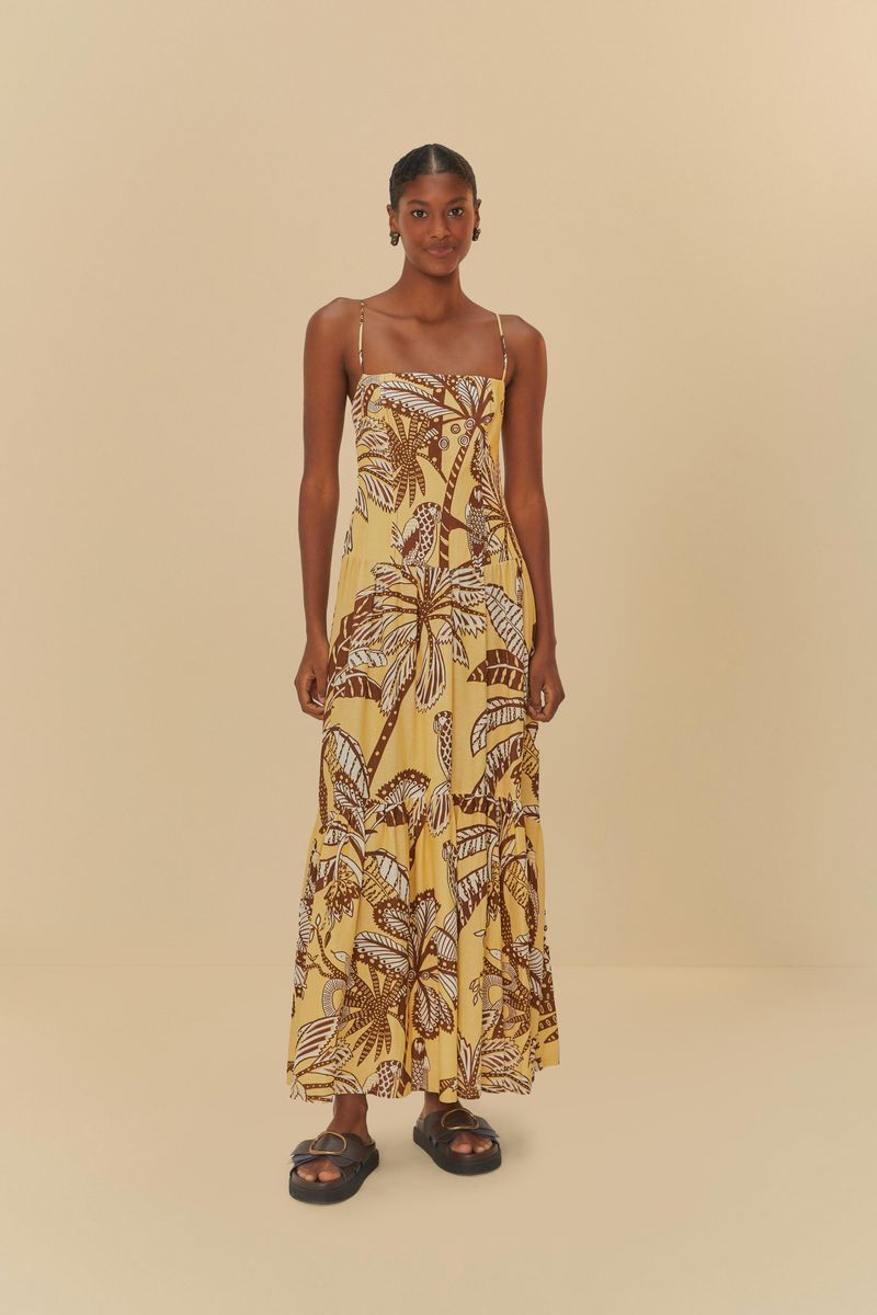 Imagen de un vestido largo con tirantes finos, estampado con motivos botánicos en tonos de amarillo y marrón, visto de frente.