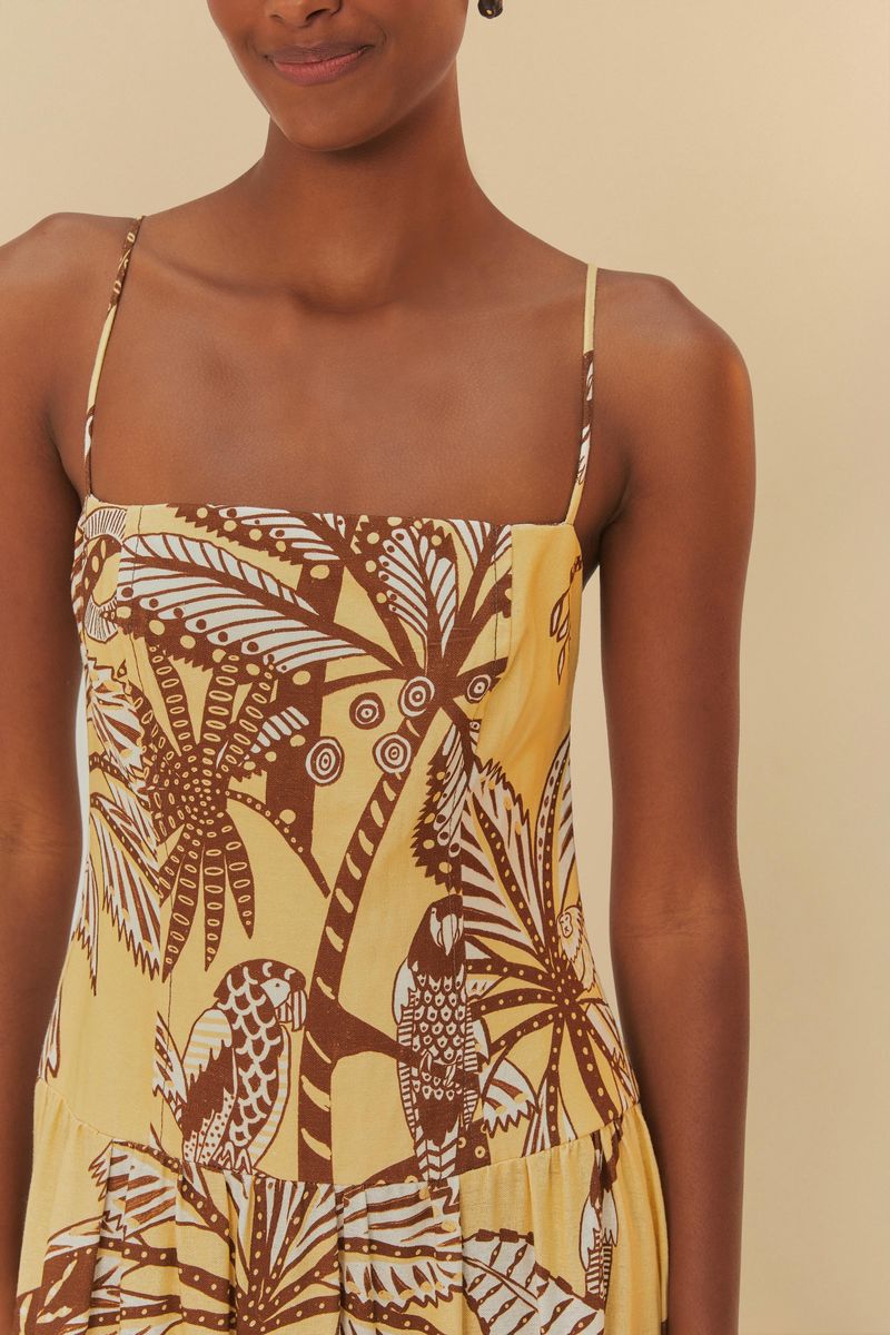 Primer plano del corpiño de un vestido estampado con motivos botánicos en tonos de amarillo y marrón, mostrando detalles de los tirantes.