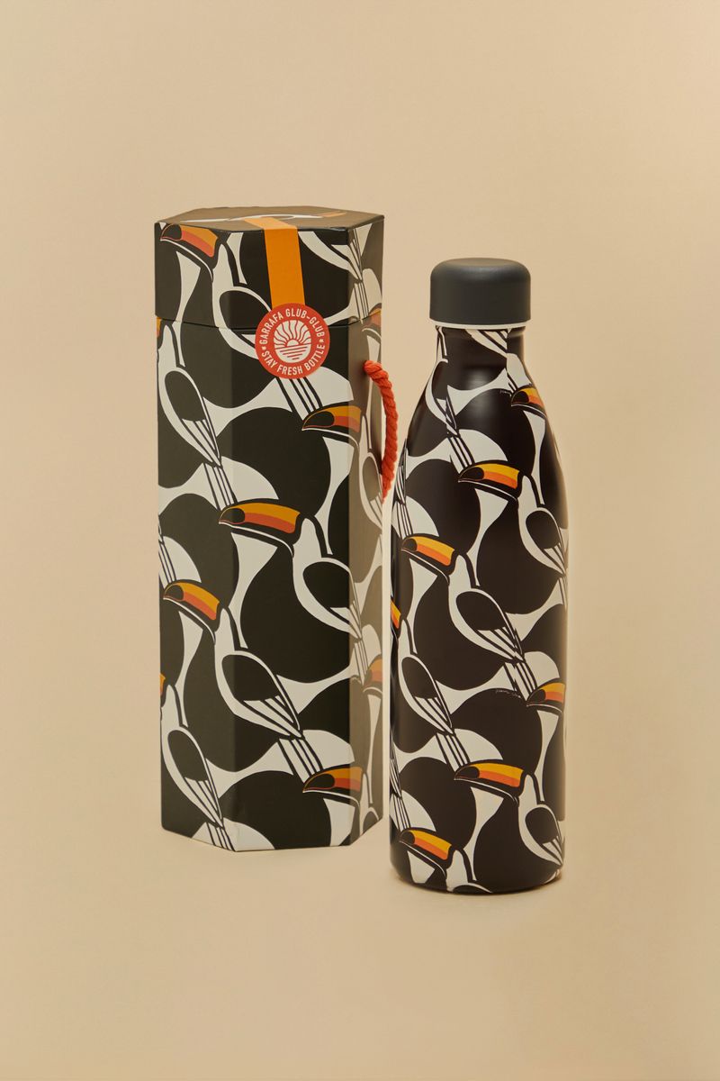 Garrafón estilizado con diseño geométrico en negro, blanco y detalles en naranja y amarillo, acompañado de empaque decorativo.