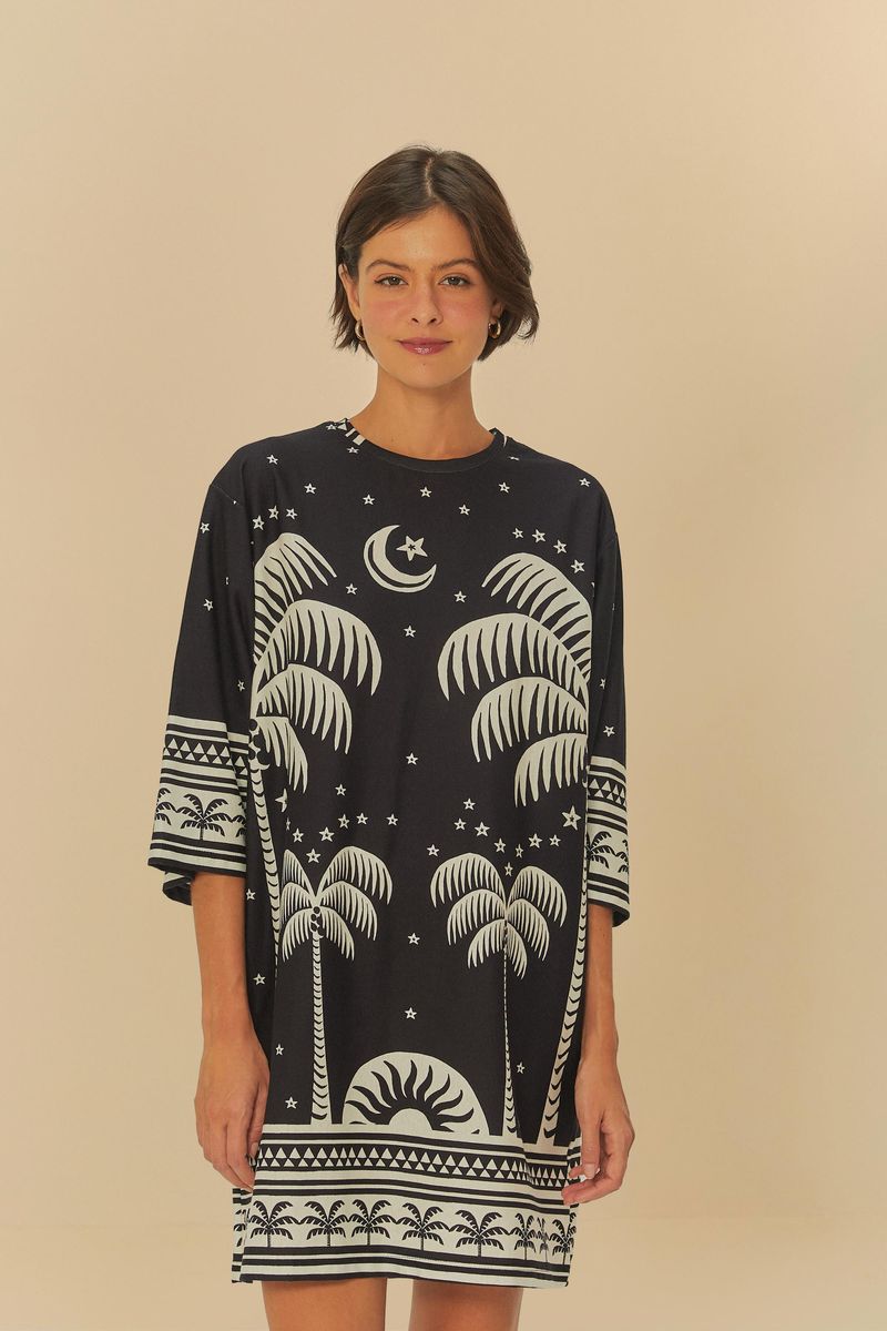 Vestido estilo camiseta con estampado de palmeras y elementos celestiales sobre fondo oscuro, visto de frente.
