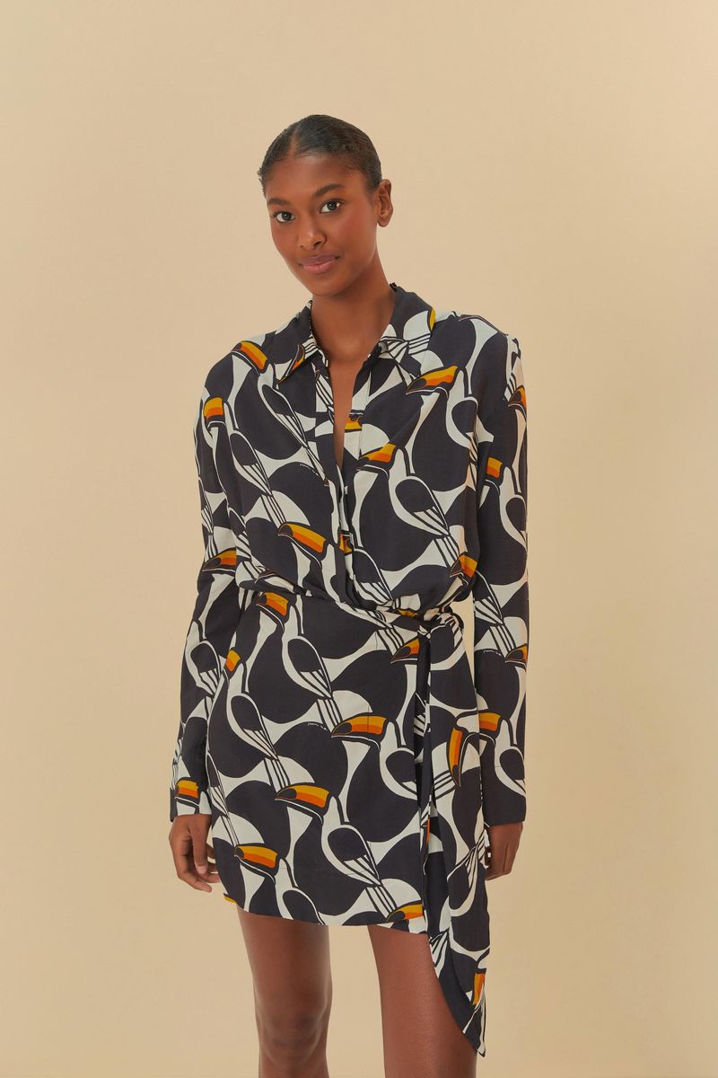 Imagen de un vestido corto con estampado geométrico en tonos de negro, blanco y naranja, con mangas largas y escote tipo chemise.
