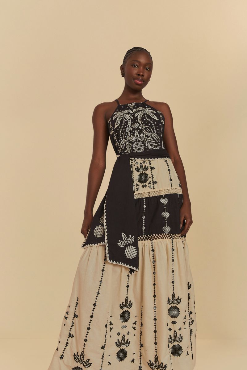 Imagen de un vestido con bordado detallado y estampado en tonos negros y beige, exhibido sobre un fondo neutro.