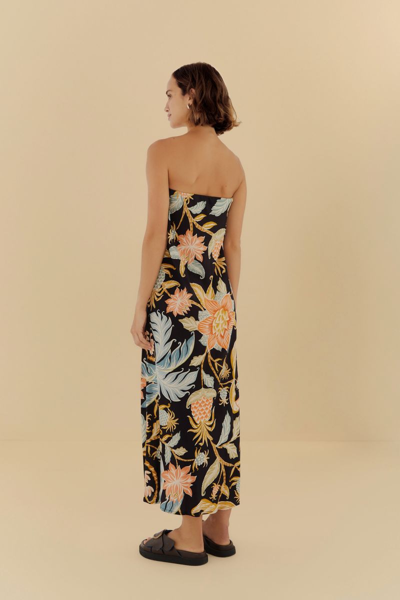 Imagen de un vestido largo estampado con fondo negro y detalles florales y botánicos, mostrando el detalle de la falda.