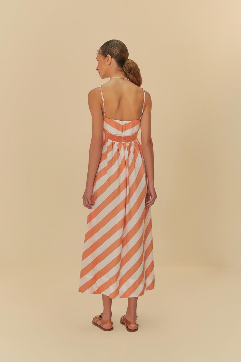 Vista lateral del vestido con tirantes finos y estampado de rayas diagonales en tonos de naranja y blanco.