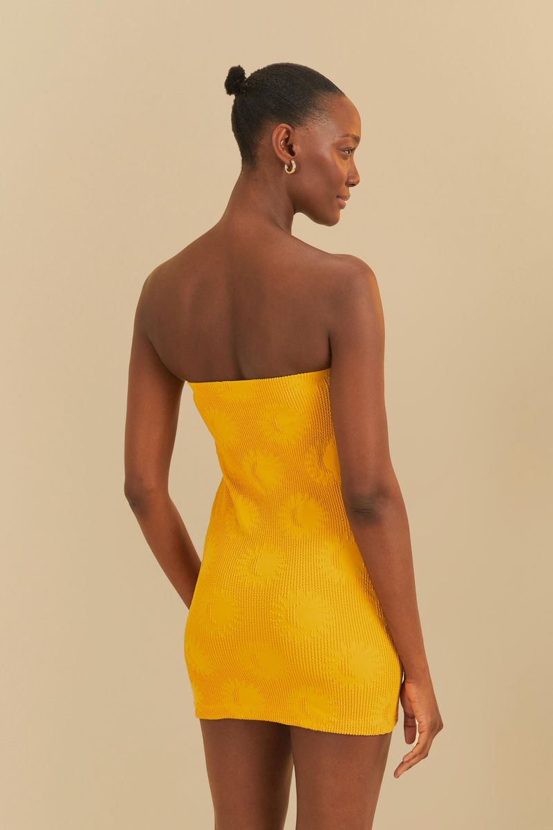 Vestido amarillo con estampado de sol, modelo de espaldas.