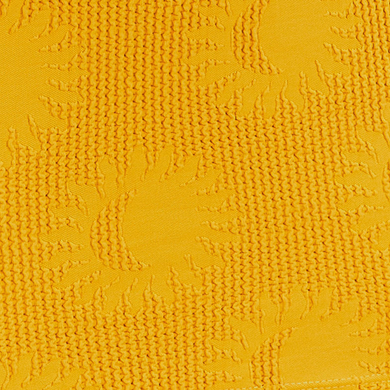 Detalle de la textura del vestido amarillo con estampado de sol.