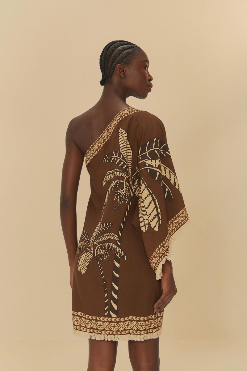 Vista trasera del vestido corto con estampado tropical sobre fondo marrón, modelo de un solo hombro.