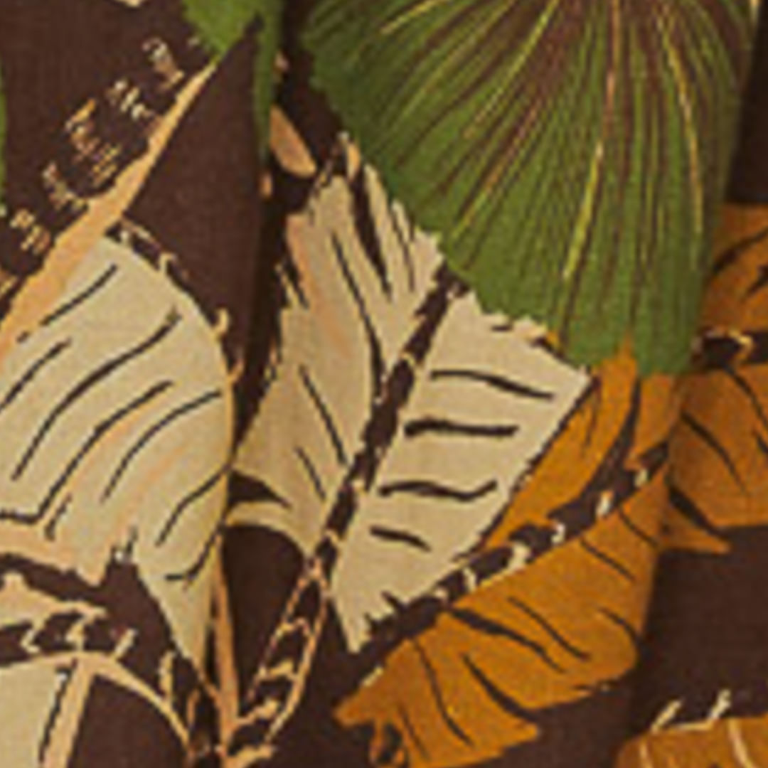 Primer plano del estampado tropical del vestido corto, evidenciando los elementos de hojas y colores vibrantes.