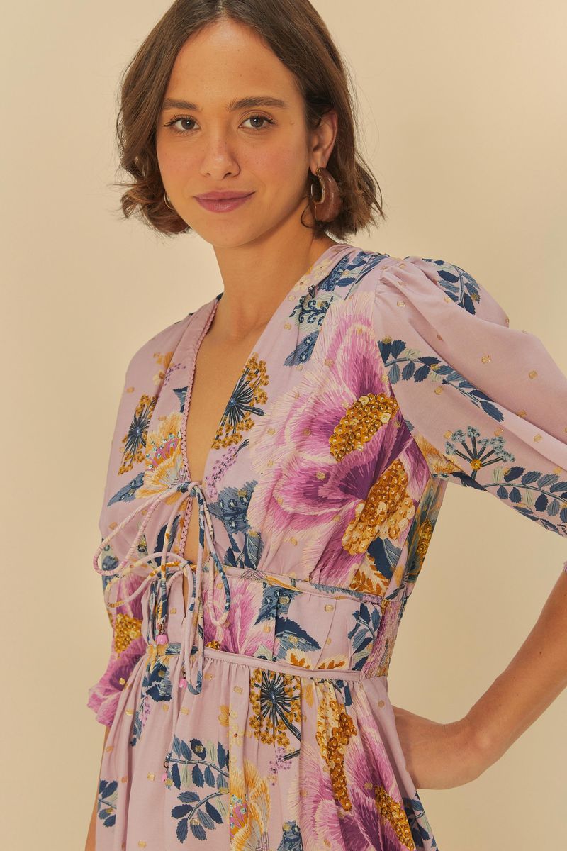 Detalle del vestido corto con estampado floral, resaltando el escote y el amarre frontal.