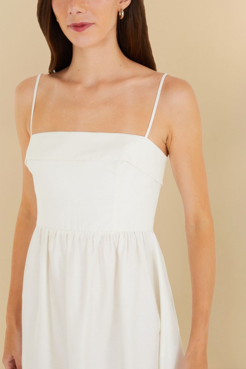 Primer plano del escote cuadrado del vestido blanco con tirantes delgados.