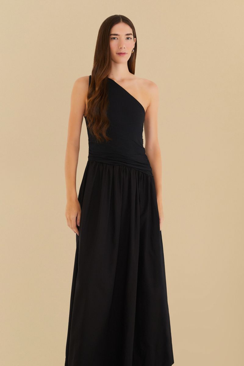 Vista frontal del vestido negro con diseño de un hombro único y falda godé, mostrando detalles del ajuste en la cintura.