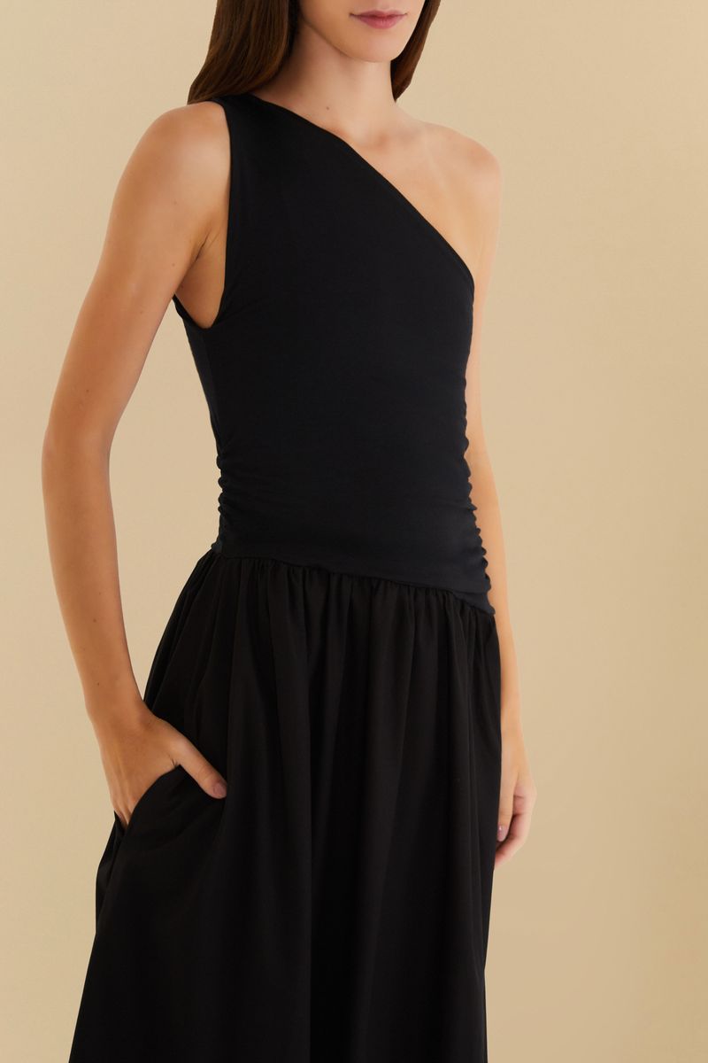 Vista de cerca del vestido negro con diseño de un hombro único, destacando la tela y el ajuste en la cintura.