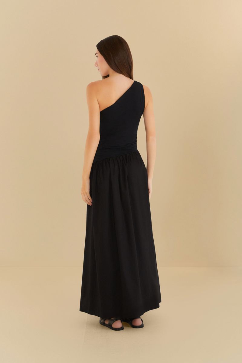 Vista posterior del vestido negro con diseño de un hombro único y falda godé, mostrando la caída de la tela.