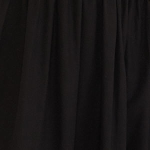 Detalle lateral del vestido negro con diseño de un hombro único, destacando el ajuste en la cintura y la tela fluida.