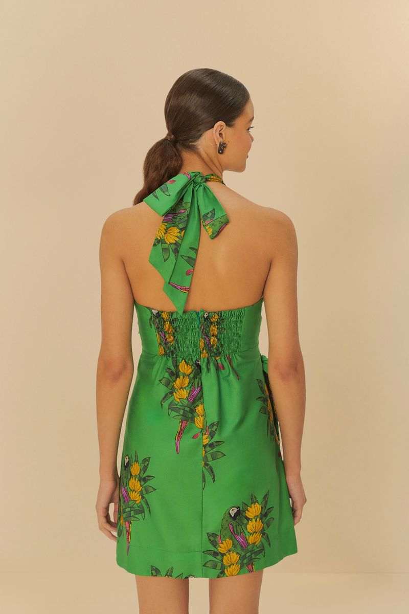Vista trasera del vestido corto verde con estampado tropical, mostrando el detalle de amarre en el cuello y el ajuste elástico en la espalda.