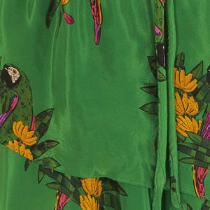 Close-up del estampado floral del vestido largo verde, con detalles en amarillo y morado.