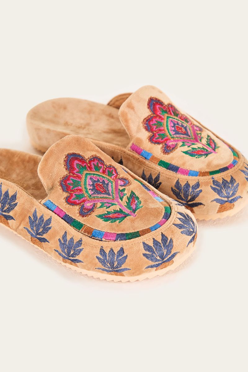 Mocasines estilo clog en terciopelo camel con bordados de tapicería vistos desde el costado.