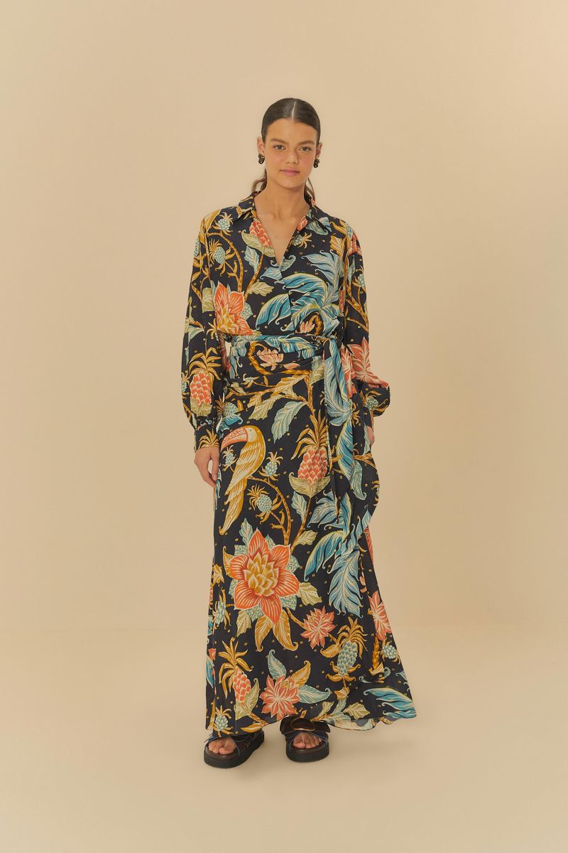 Modelo luciendo un vestido estampado con patrón floral y botánico, largo hasta los pies, mostrado sobre un fondo neutro.