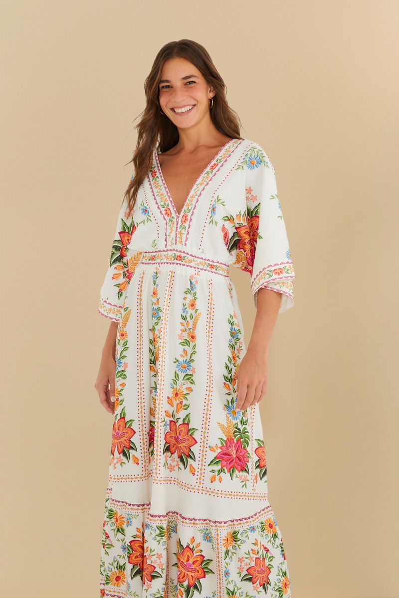 Vestido midi con estampado floral en fondo blanco, escote en V y mangas amplias.