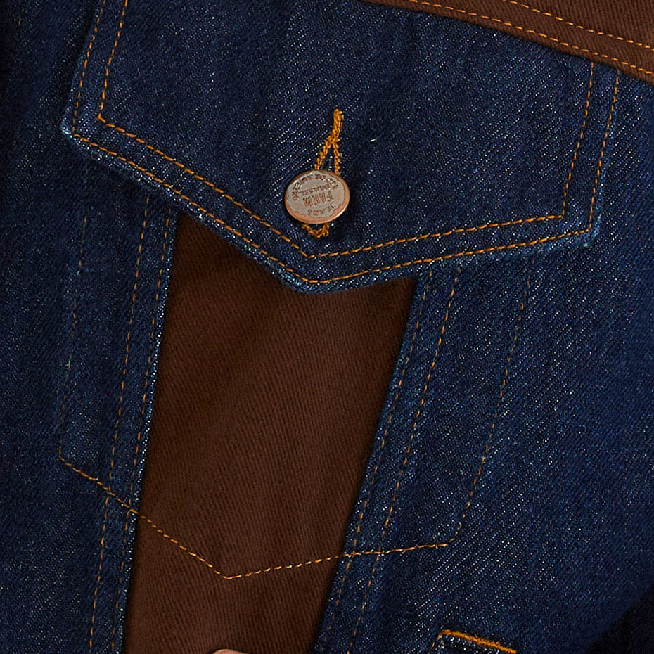 Acercamiento de los bolsillos con solapa y costuras de la chaqueta jean duo sarga marrón.