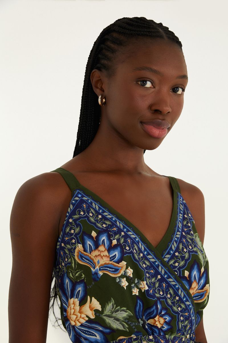Vestido corto con estampado floral vibrante sobre fondo verde, con escote cruzado y tirantes anchos.