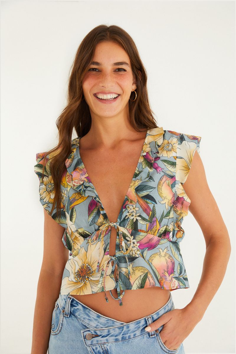 Imagen de una blusa estampada con flores tropicales, vista frontal con amarre y volantes.