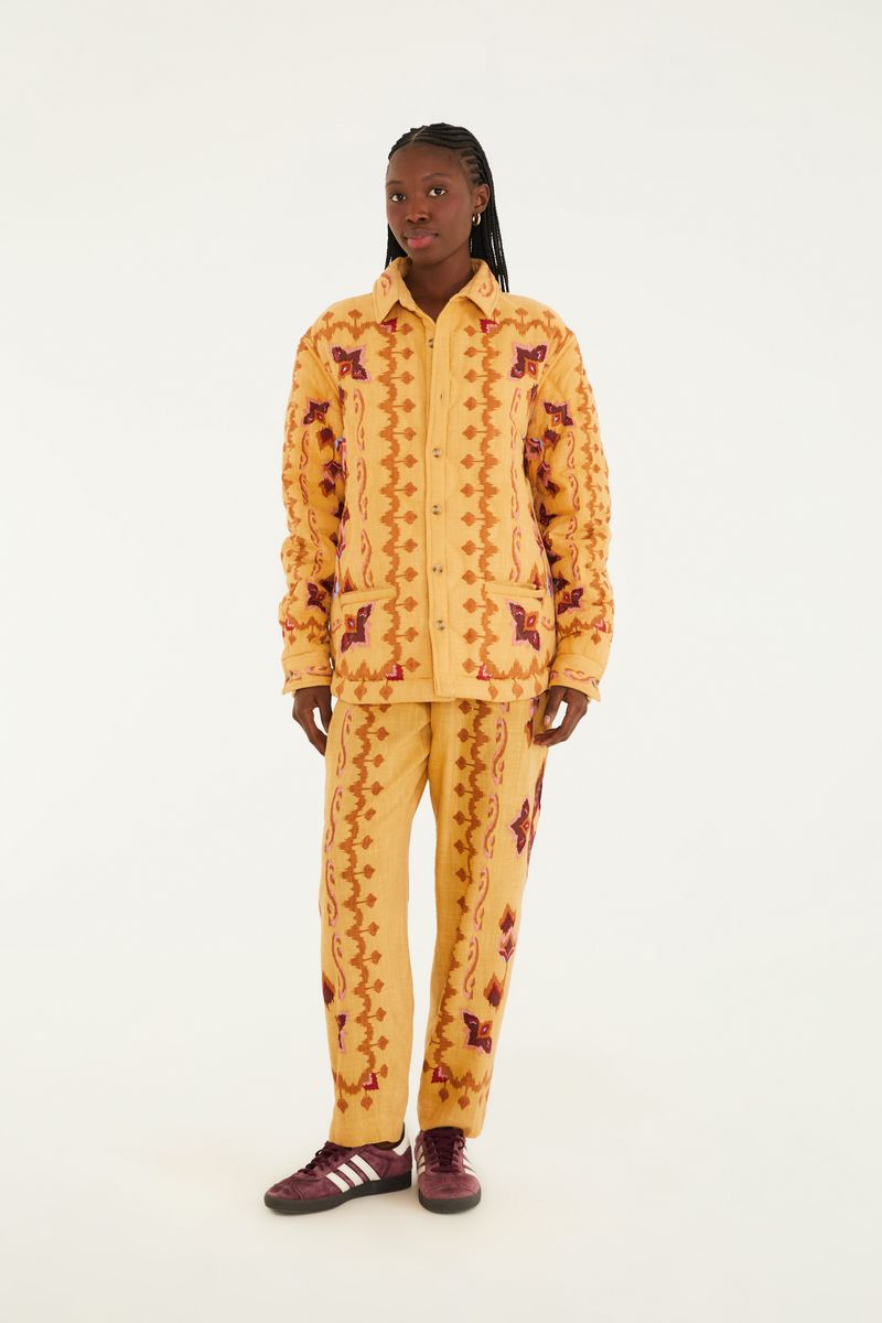 Imagen de un pantalón estampado con diseño geométrico en tonos ocre, rojo y marrón, visto de frente.