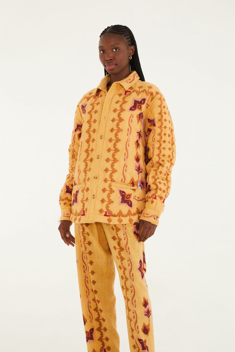 Imagen de un pantalón estampado con diseño geométrico en tonos ocre, rojo y marrón, visto de lado.