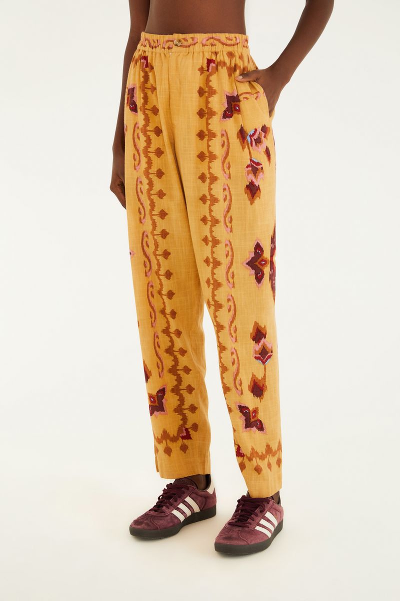 Imagen de un pantalón estampado con diseño geométrico en tonos ocre, rojo y marrón, visto de espaldas.
