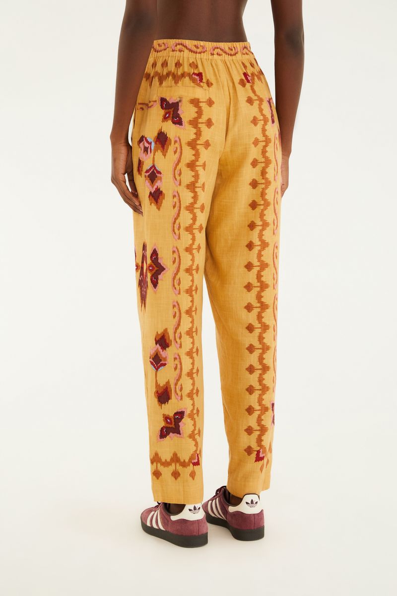 Imagen de un pantalón estampado con diseño geométrico en tonos ocre, rojo y marrón, detalle de la cintura con elástico.