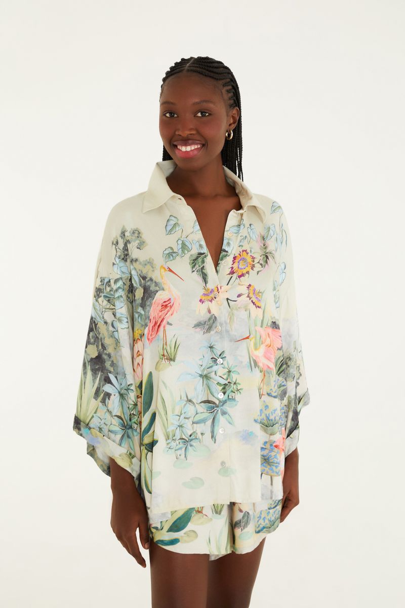 Modelo usando un conjunto con camisa y short estampados con temática tropical.