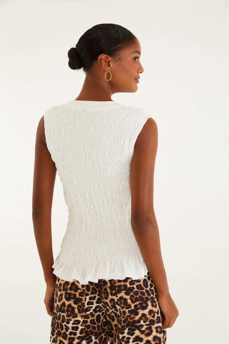 Blusa blanca con textura lastex vista desde atrás, sin mangas y borde recto.