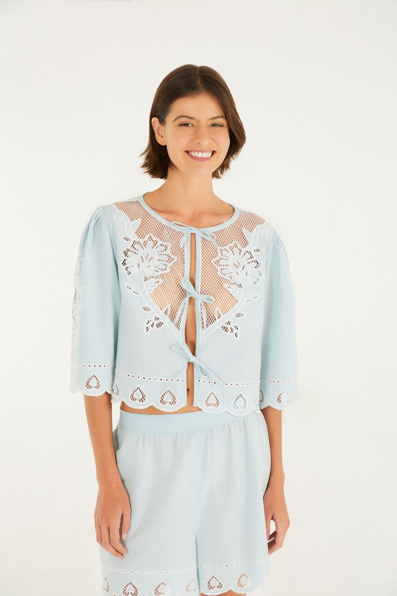 Imagen de una blusa bordada azul claro con detalles florales y mangas abombadas.