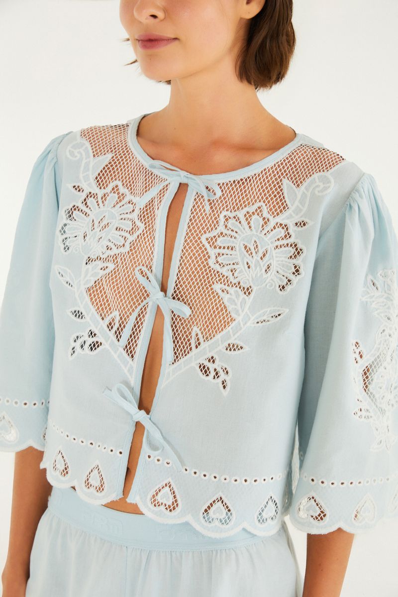 Detalle del bordado floral en la blusa azul claro.