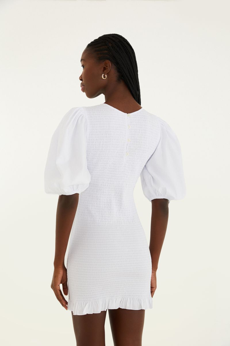Vista trasera del vestido corto blanco con mangas abullonadas y detalle de smock.