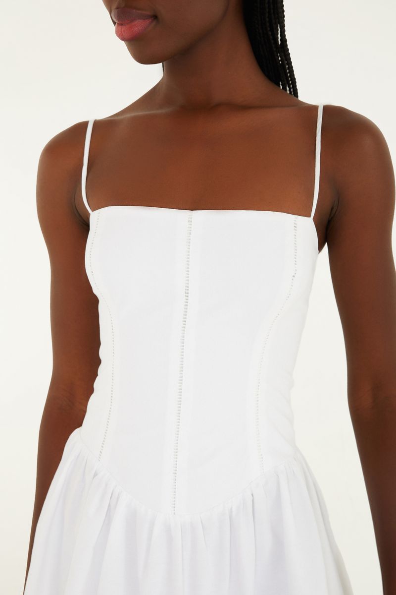 Detalle del corsé del vestido corto blanco con tirantes delgados.