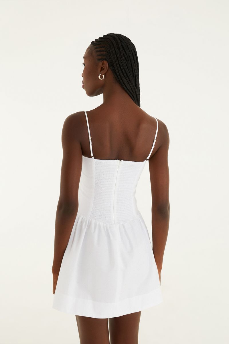 Vista lateral del vestido corto blanco con tirantes delgados.
