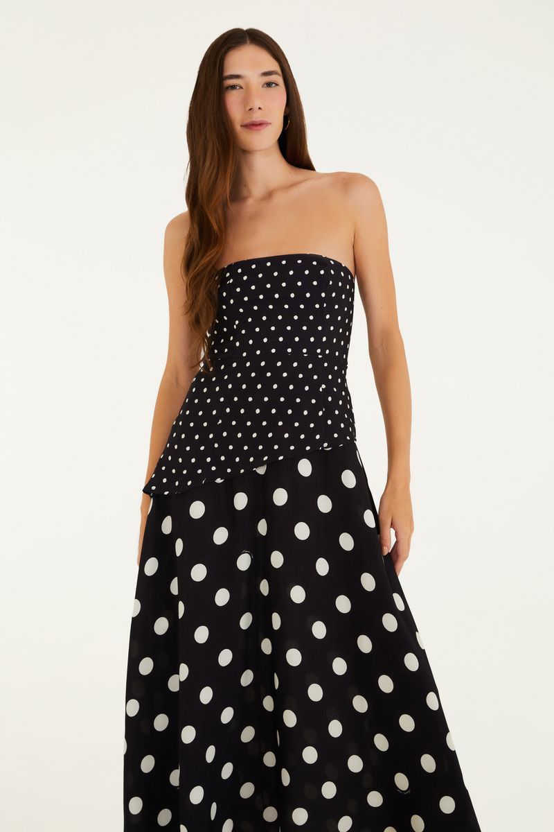 Vestido negro con estampado de puntos blancos, modelo sin mangas, largo midi, mostrado en pose lateral.