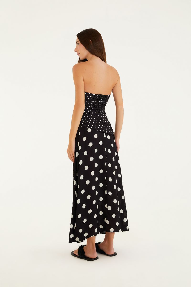Vista trasera del vestido negro con estampado de puntos blancos, modelo sin mangas, largo midi.